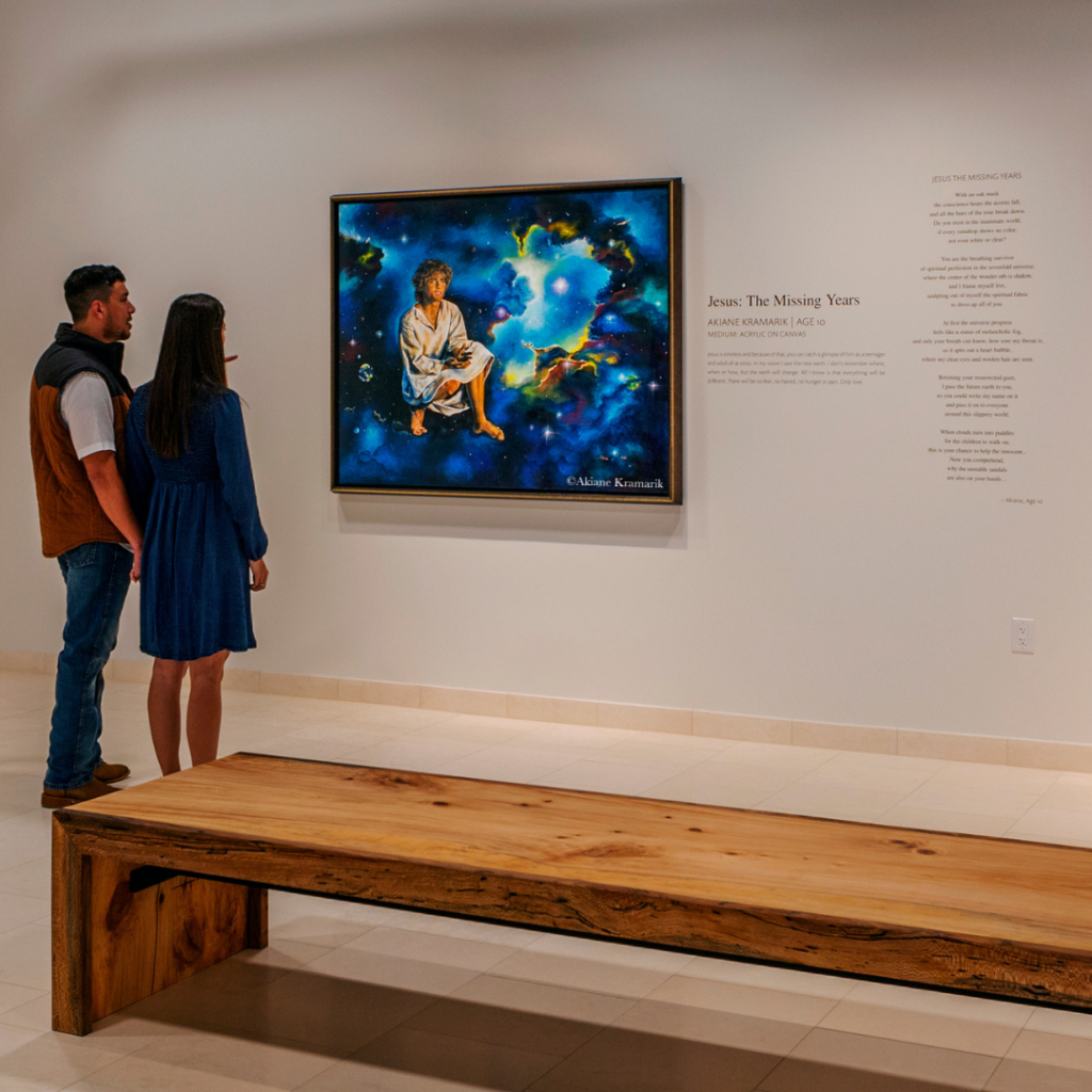 Guest reflecting on Akiane Kramarik’s Jesus: The Missing Years painting, depicting a teenage Jesus with a cosmic backdrop at Beloved Gallery.