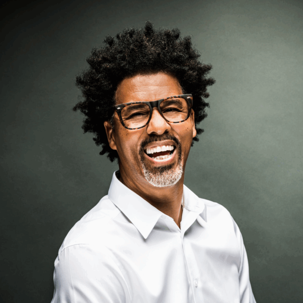 Portrait of Bradley Rapier, 2025 Featured Speaker at the Belóved Gallery Symphony of Art, smiling broadly in a white dress shirt against a dark green background.