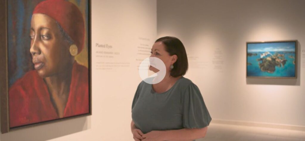 A woman stands in an art gallery, looking at a large portrait of a woman in a red headscarf. Another painting of an island is visible on the wall behind her. A play button overlay is centered on the image.
