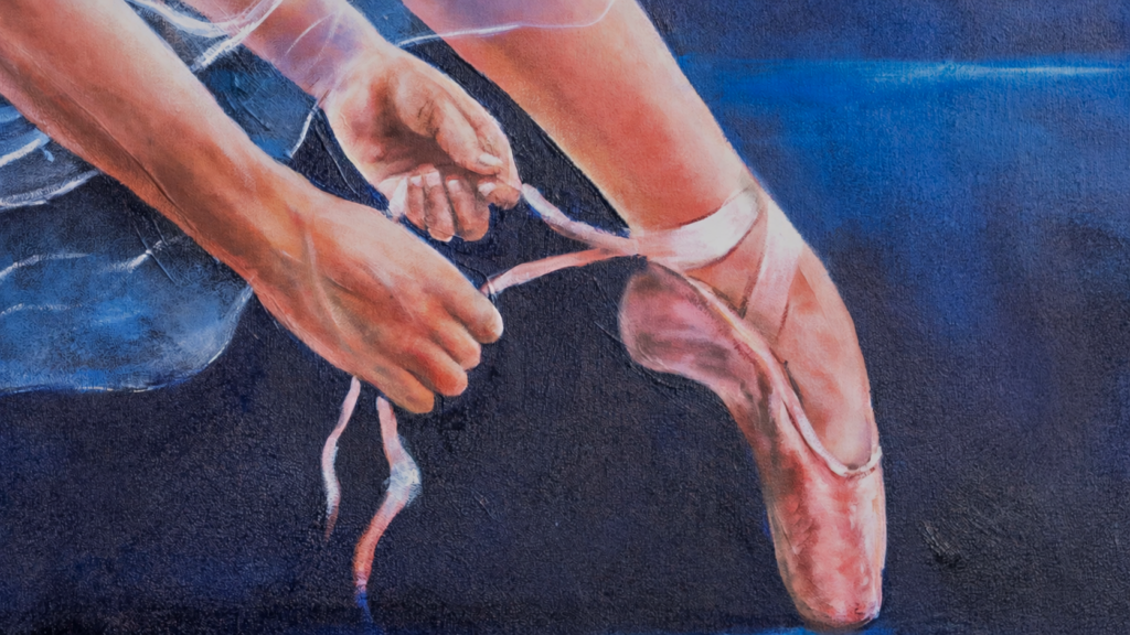 A ballerina ties the ribbon of a pink pointe shoe.